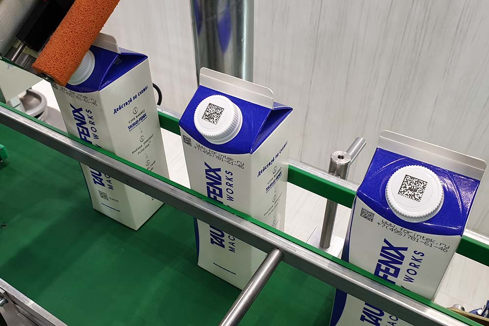 Образец верхнего нанесения стикеров с кодом даты матрикс на колпачки пакетов молока на конвейере