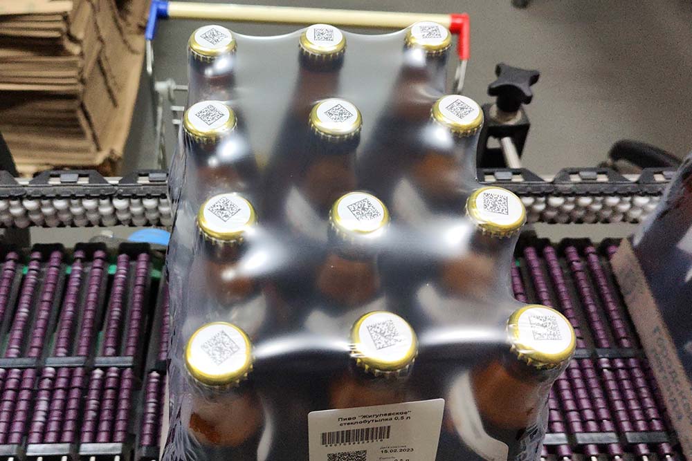 Упаковка бутылкок пива на ковейере с кодом дата матрикс