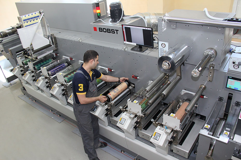Оператор на производственной линии BOBST настраивает оборудование для печати самоклеящихся этикеток