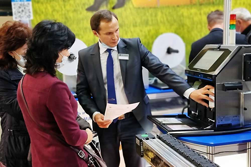 Специалист Форинтека демонстрирует работу каплеструйного принтера Hitachi на выставке Агропродмаш