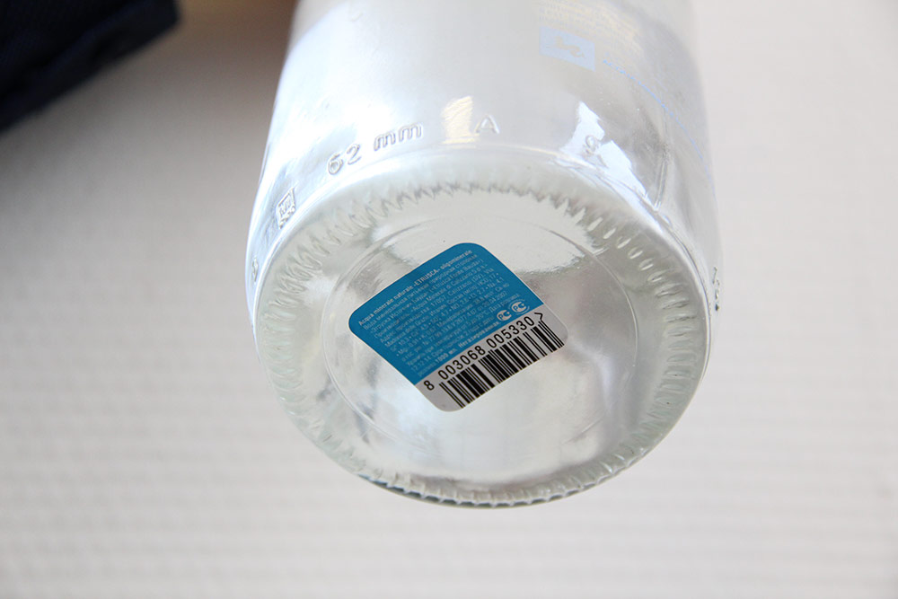 Приведен пример нижнего этикетирования дна стеклянной бутылки цилиндрической формы